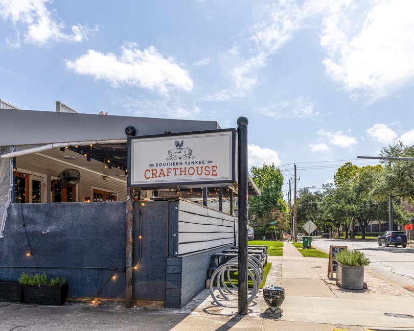 Southern Yankee Crafthouse sign and outdoor patio with string lights, seen from a sunny street.